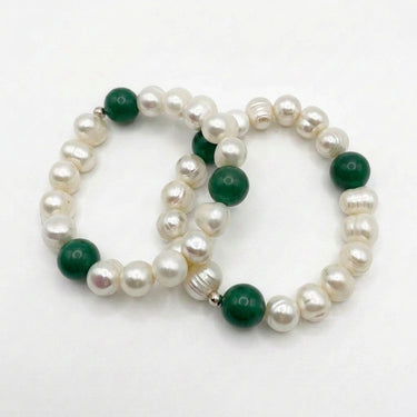 A beaded stretch bracelet featuring lustrous white baroque pearls and deep green round beads, including one malachite-style green bead, displayed on a clean white background.