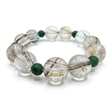 A beaded stretch bracelet featuring faceted clear rutilated beads with visible brown needle-like inclusions, accented by small round dark green beads, shown on a plain white background.