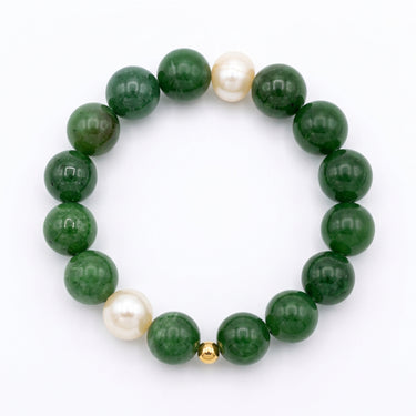 A beaded stretch bracelet featuring glossy dark green jade beads, two white freshwater pearls, and onr small gold spacer beads