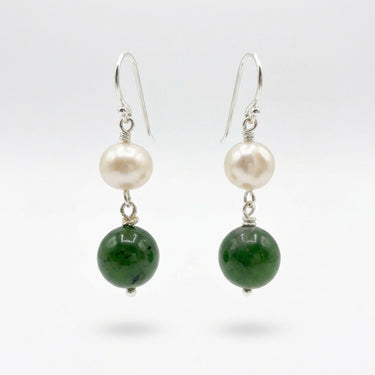 A pair of dangle earrings. Each earring has a white pearl, a green jade bead, and silver hooks.