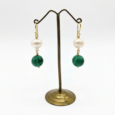 A pair of dangle earrings  Each earring features a white pearl, a green malachite stone bead, and gold hooks.