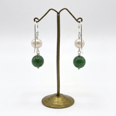 A pair of drop earrings. a white pearl, a silver connector, and a round jade bead dangling below.