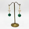 A pair of drop earrings with a white pearl, a green malachite bead, and gold hooks.