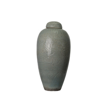 Decorative ceramic urn with intricate patterns on a sage green background