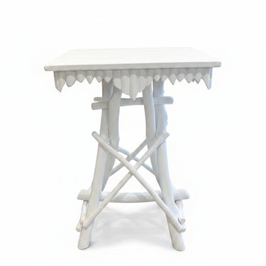 A white wooden bedside table with a scalloped apron and crossed legs