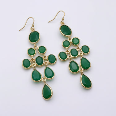 Green teardrop earrings with gold accents on a white stone surface