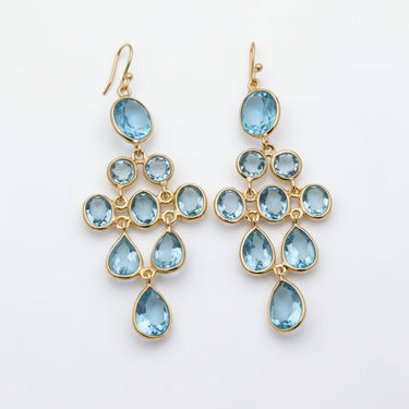 Gold earrings with blue gemstones on a marble surface