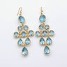 Gold earrings with blue gemstones on a marble surface