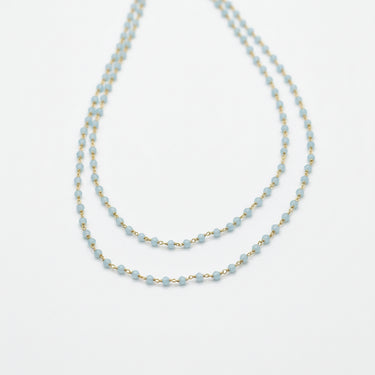 Beaded necklace with gold chain on a dark fabric background