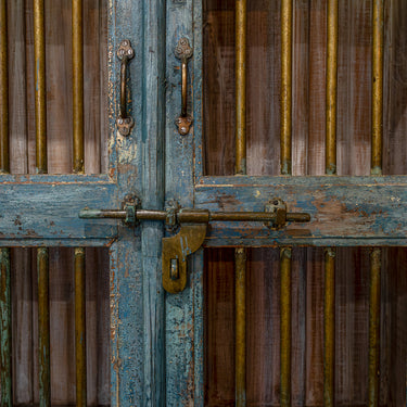 Close-up of an old wooden door with metal bars and a lock.