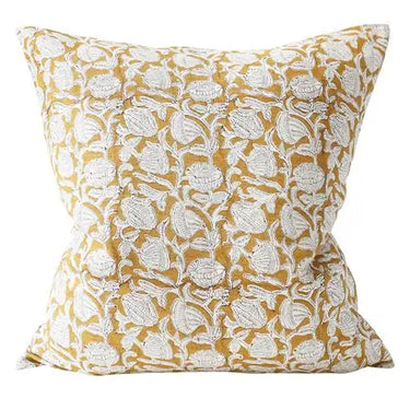 Decorative pillow with white floral pattern on a mustard yellow background