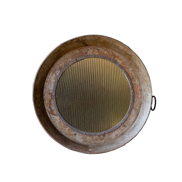 A round rustic metal wall mirror with a distressed, weathered finish and  loop handle